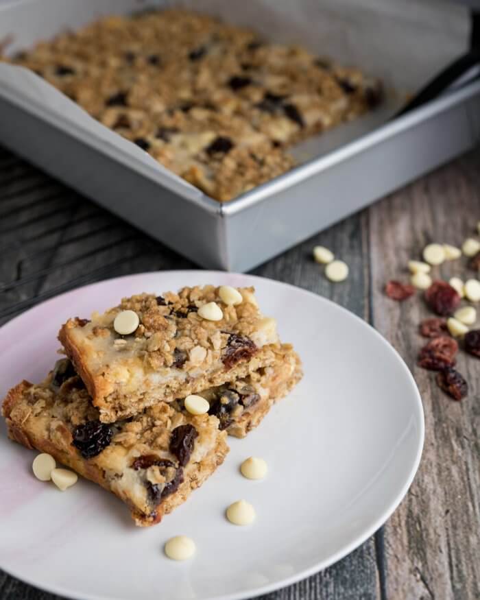 white chocolate cranberry oat bars stacked on a white plate