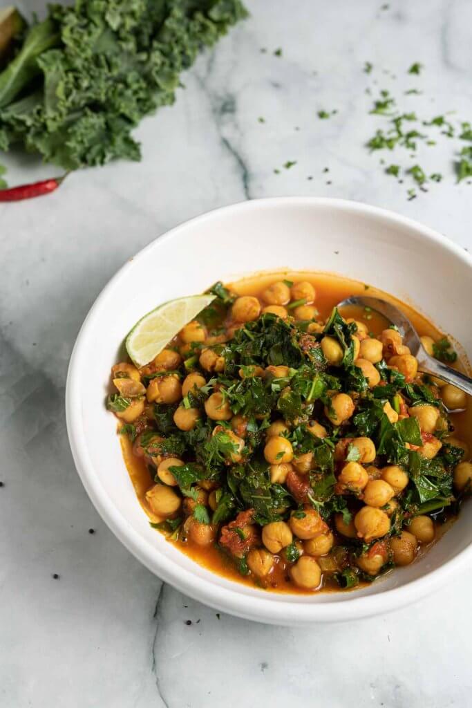 chickpea and kale stew with tomatoes and chillies in a white bowl