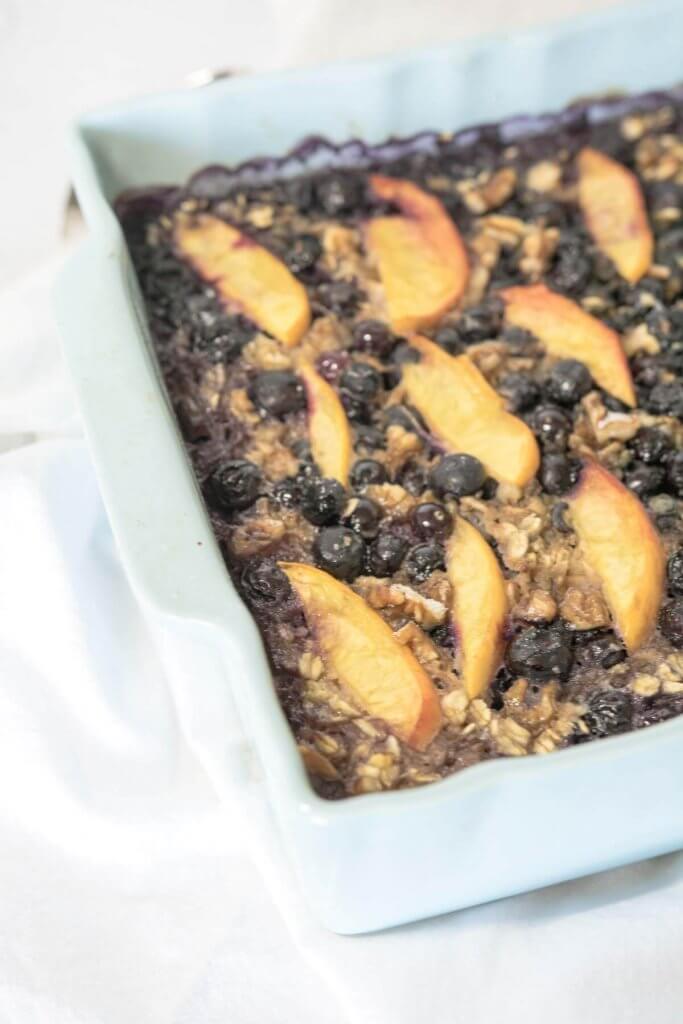 baked banana oatmeal with blueberries and sliced peaches