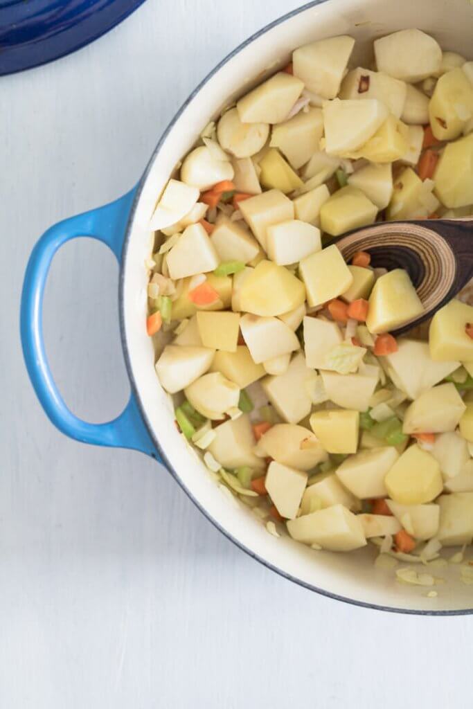 garlic cloves and potatoes and vegetables in a soup pot