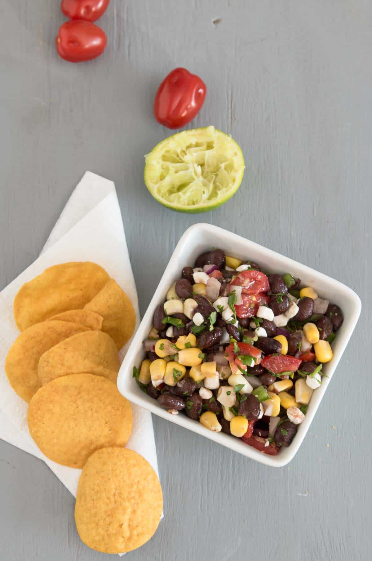 black bean and corn dip with feta cheese and tomoatoes served with corn chips