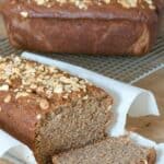 peanut butter banana bread sliced on parchment paper, peanuts sprinkled on top