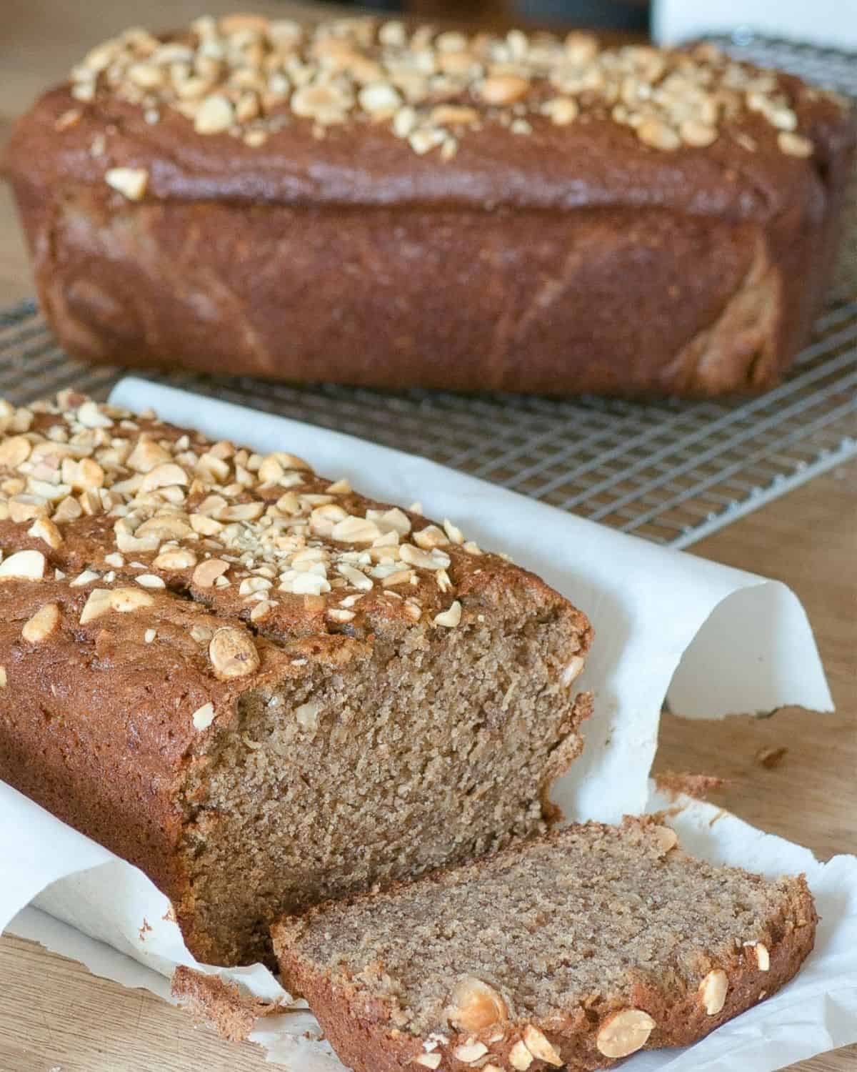 peanut butter banana bread sliced on parchment paper, peanuts sprinkled on top
