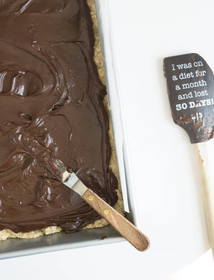 spreading fudge on top of oat cookie crust