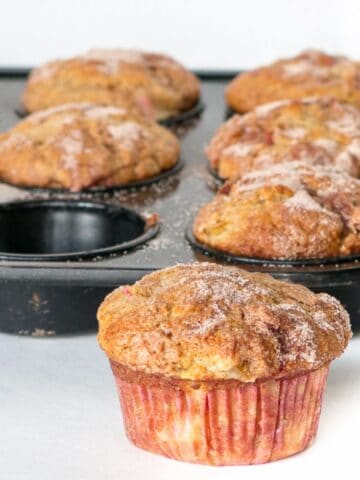 rhubarb muffin made with greek yogurt with a tray of baked muffins in background