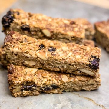 a stack of almond and cherry granola bars on a cutting board