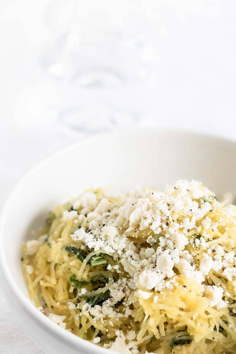 A bowl of cooked spaghetti squash with feta and kale.