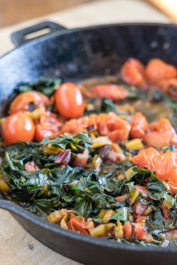 swiss chard and blacken cherry tomatoes in a cast iron skillet
