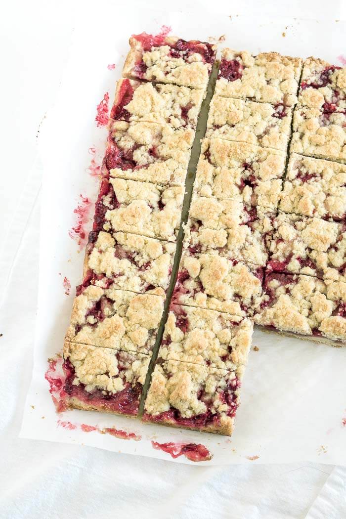 a tray of strawberry crumb cookie bars being cut for serving