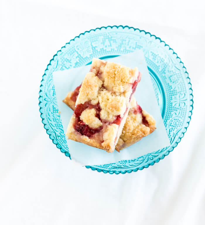 a stack of strawberry crumb bars on a blue glass plate