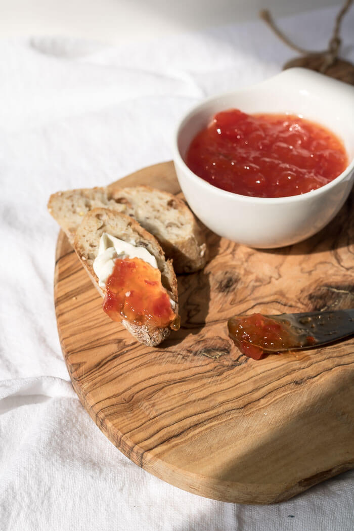 red pepper jam on a cutting board with toast and cream cheese