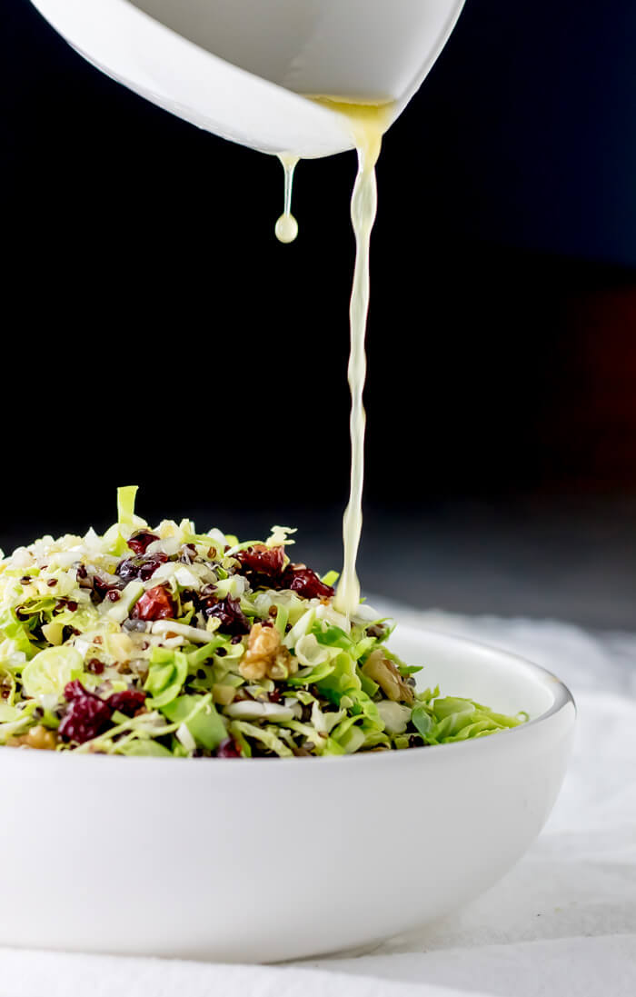 brussels sprout and quinoa salad with lemon dressing poured over top