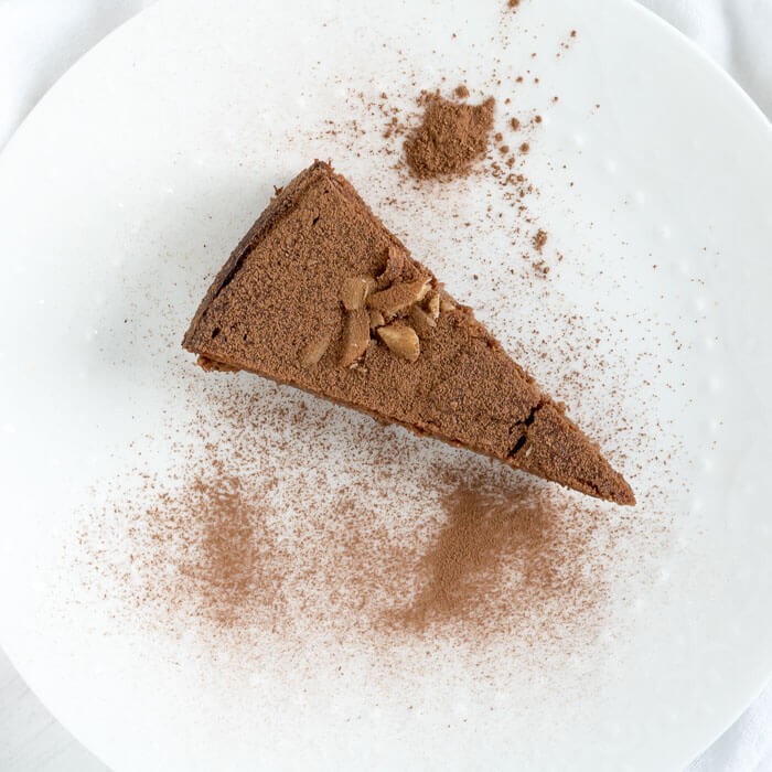 a slice of dark chocolate ricotta cake on a plate with cocoa