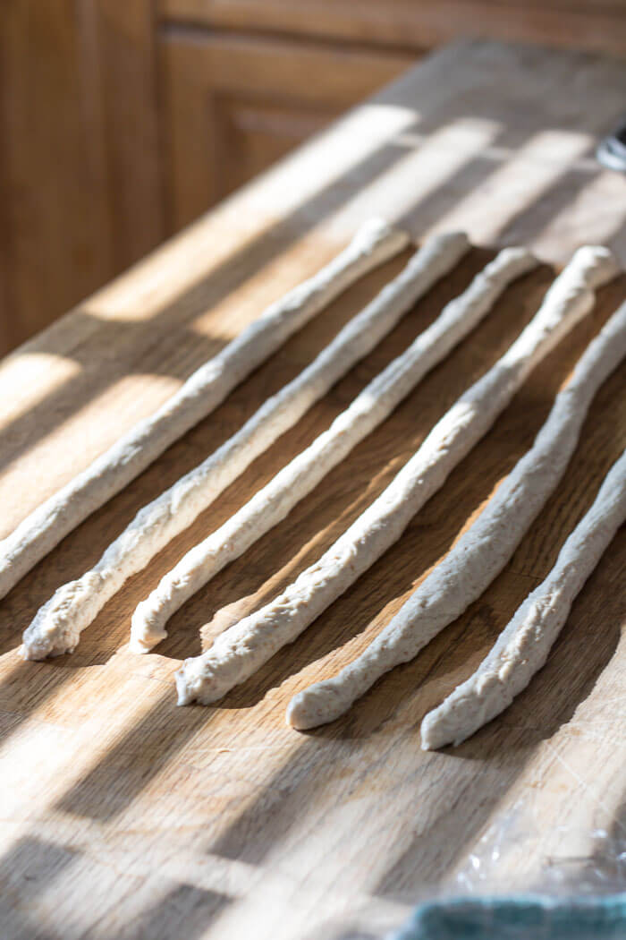 logs of pretzel dough lined up on a wood counter top