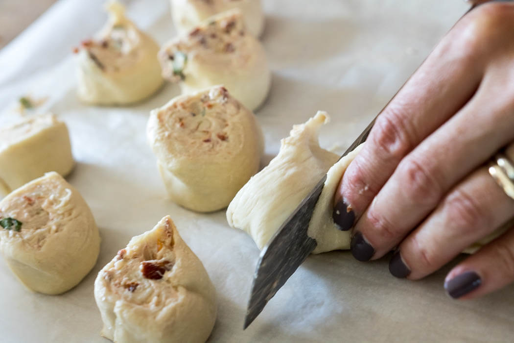 cutting the puffed pastry to make sundried tomato rolls