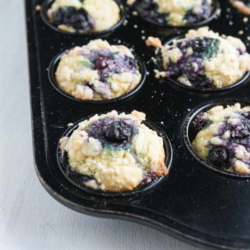 blueberry muffins in a muffin tin, muffins have crumble streusel topping