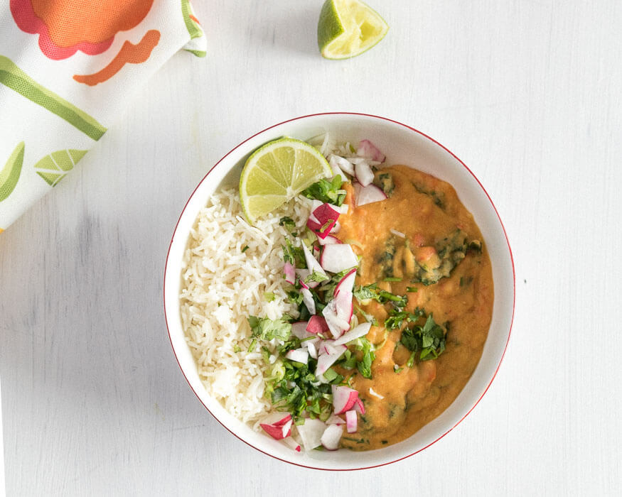 Coconut Red Lentil Curry in a bowl with rice and fresh squeesed lime.
