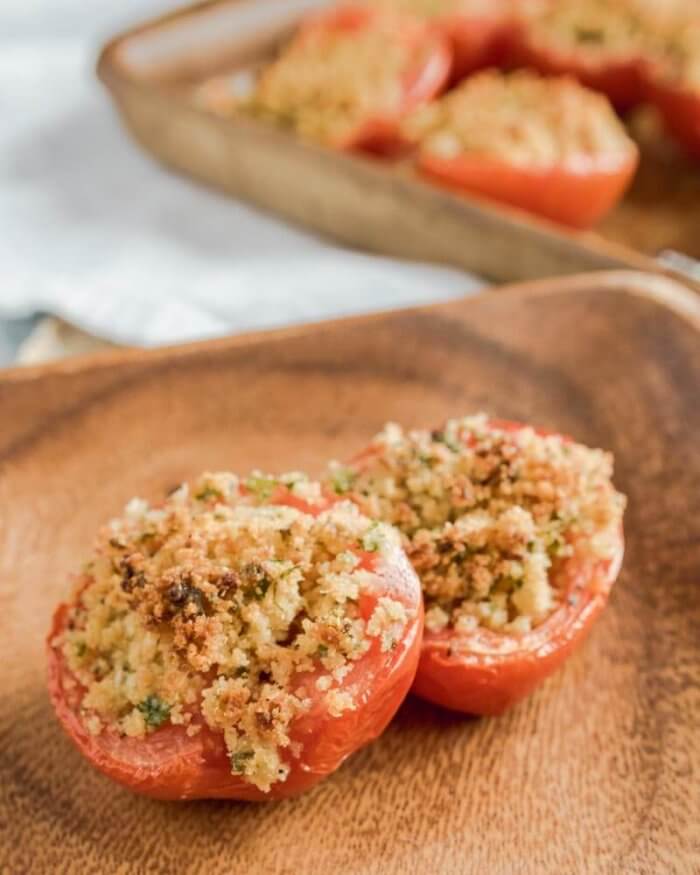 a serving of baked tomatoes on a wooden plate