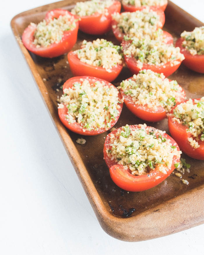 parmesan stuffed tomatoes ready for baking on a stone baking tray