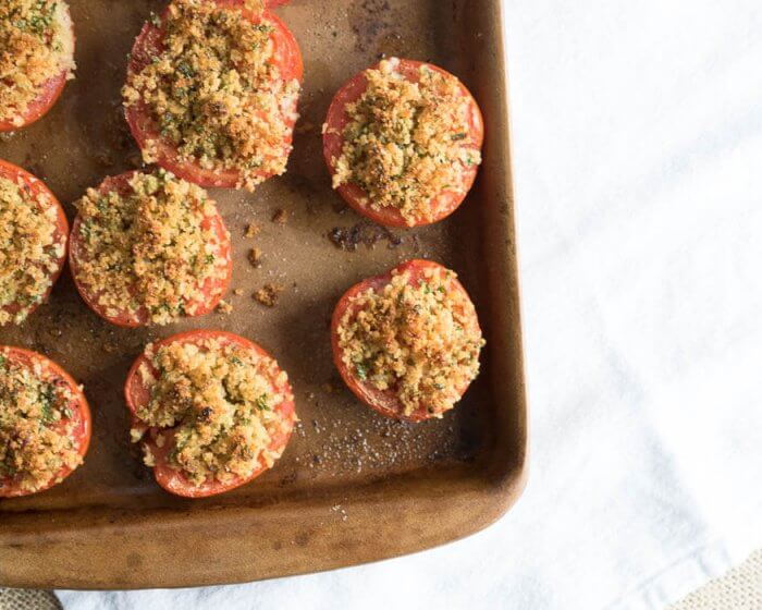 parmesan stuffed tomatoes on a stone baking tray with crisp and golden tops