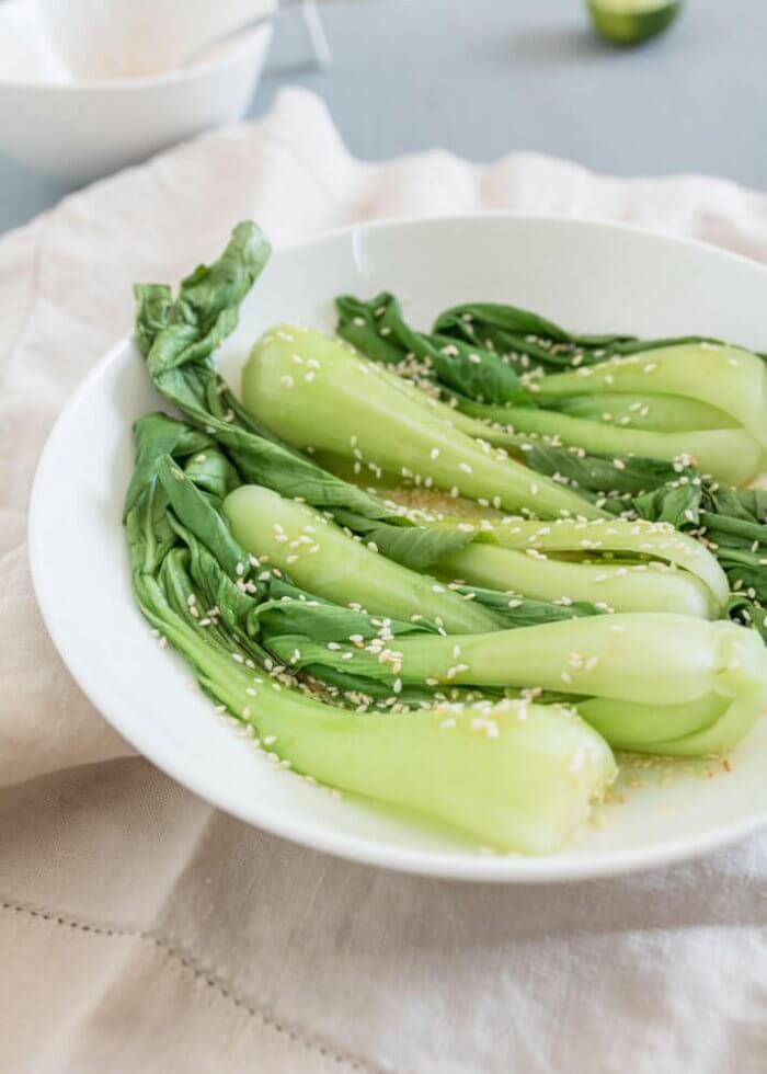 steamed baby bok choy with sesame seeds on a while plate 