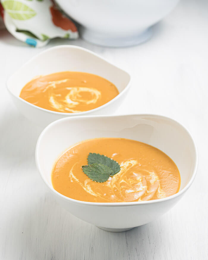 two bowls creamy carrot soup with coconut milk