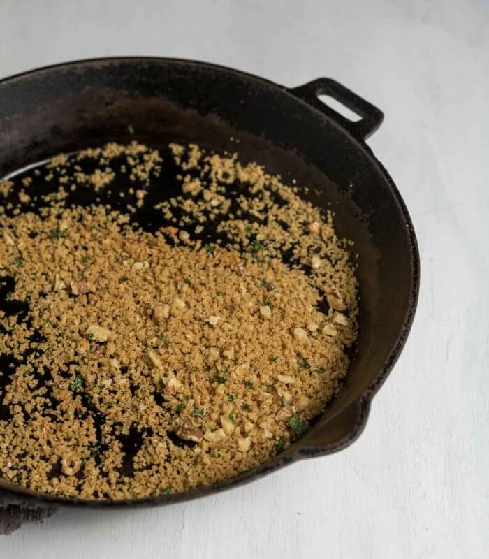 toasting breadcrumbs and walnuts in a cast iron skillet for a pasta topping