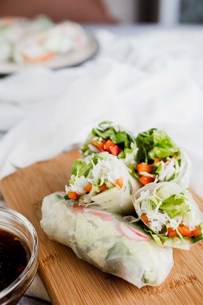 fresh salad wraps on a wooden board with soy dipping sauce