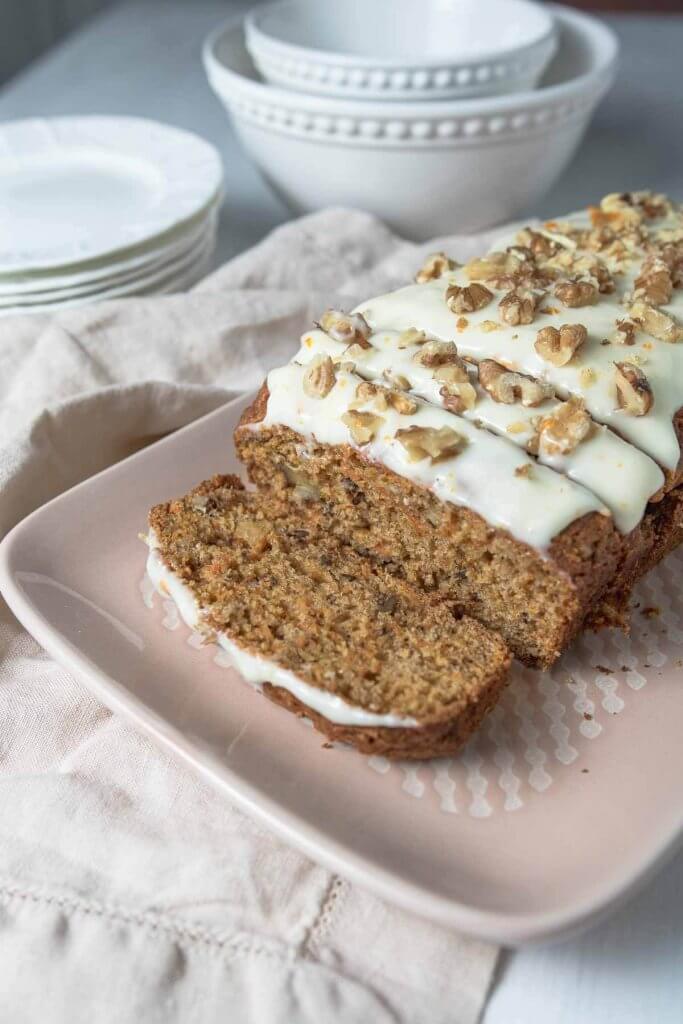 carrot loaf with cream cheese frosting and walnuts on a plater 
