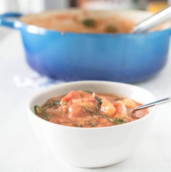 creamy tomato gnocchi soup with spinach , blue soup pot in background