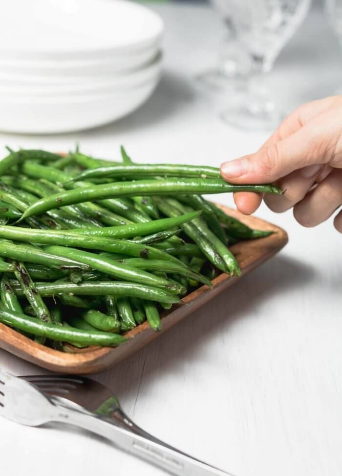 sesame green beans served, picture shows a hand stealling a few from the platter