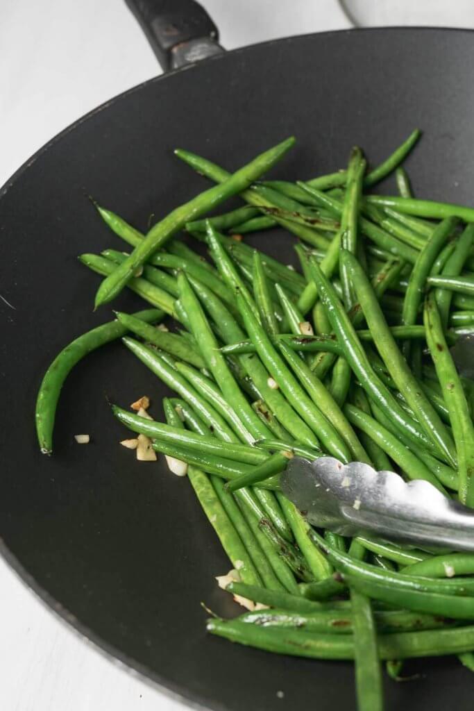 in a large wok, green beans with garlic