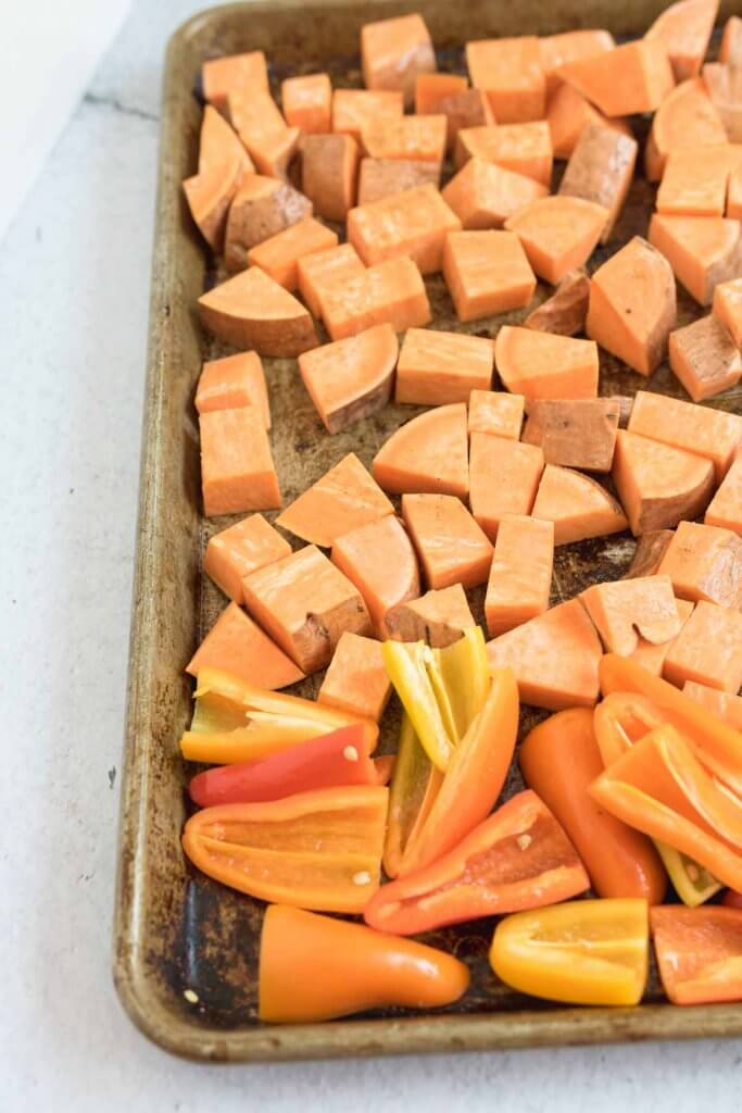 sweet potatoes and and sweet peppes on a baking sheet reading for roasting