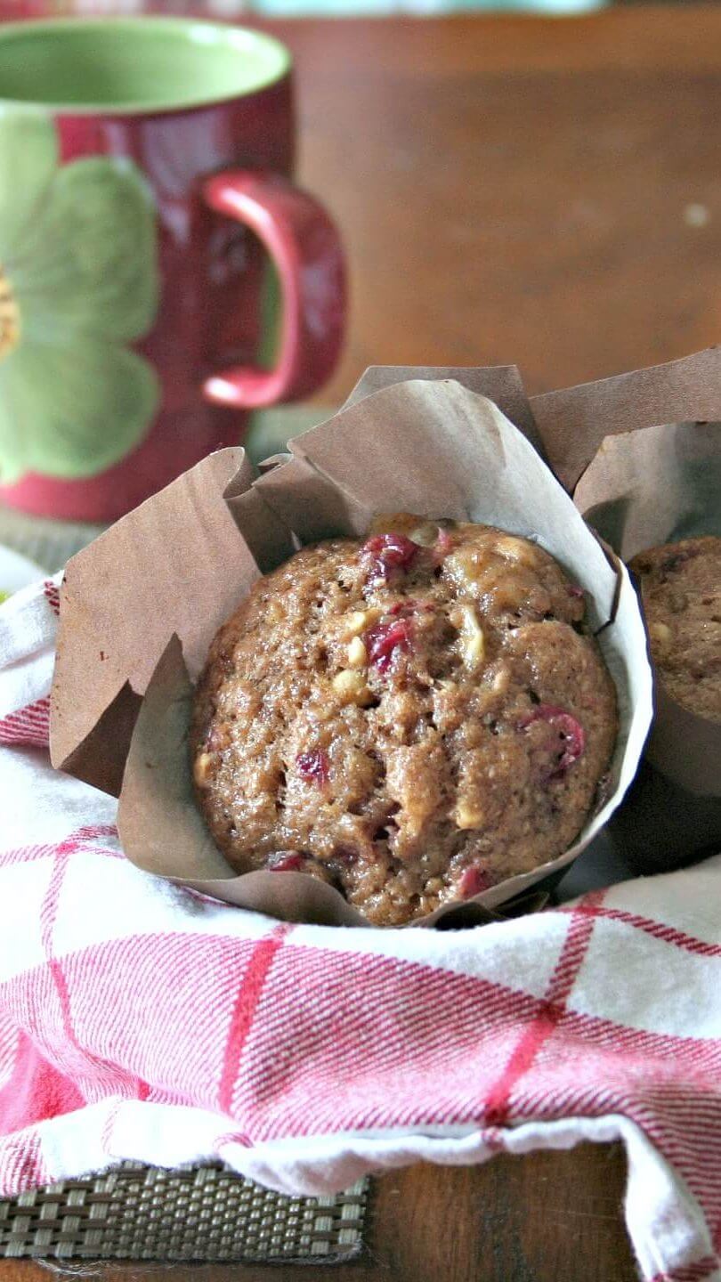 cranberry cashew muffins in a red and white checked tea towel, a cup of coffee in the background
