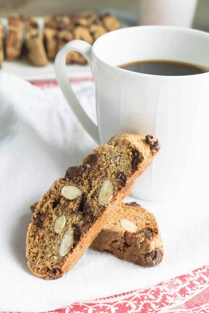 two whole wheat biscotti and almond cookies stacked against a cup of coffee