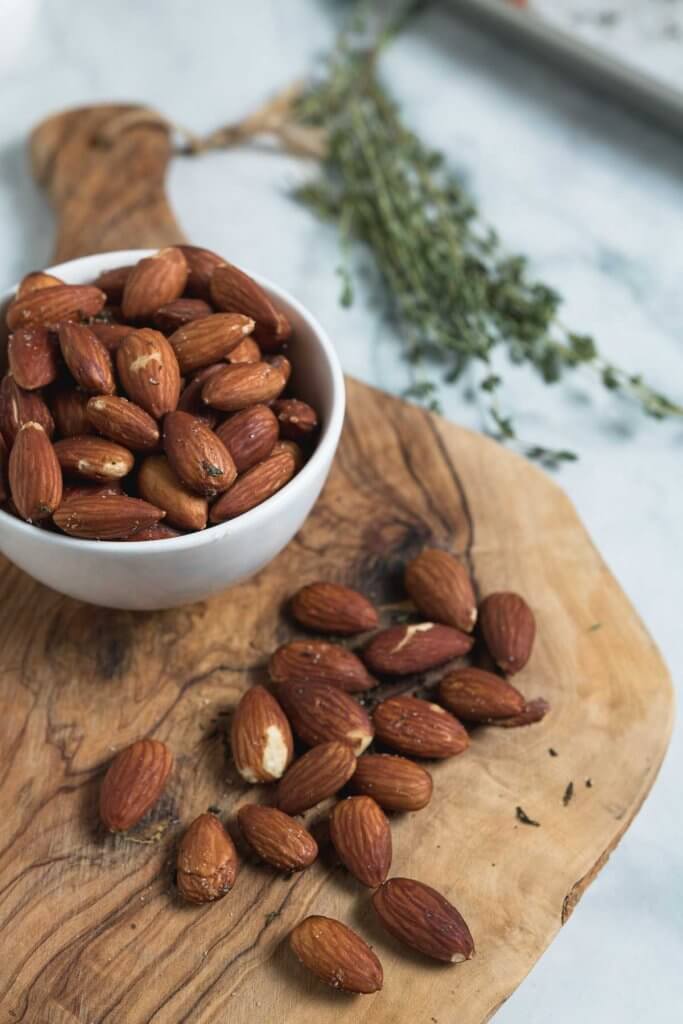 thyme and see salt roasted almonds on a serving plater with thyme in the background