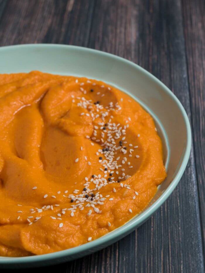 carrot mash with miso and sesame seeds in a green bowl