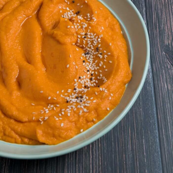 carrot mash with miso and sesame seeds in a green bowl