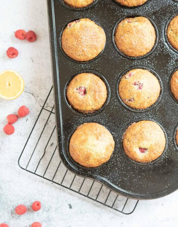raspberry lemon muffins in a muffin tin on a cooling rack