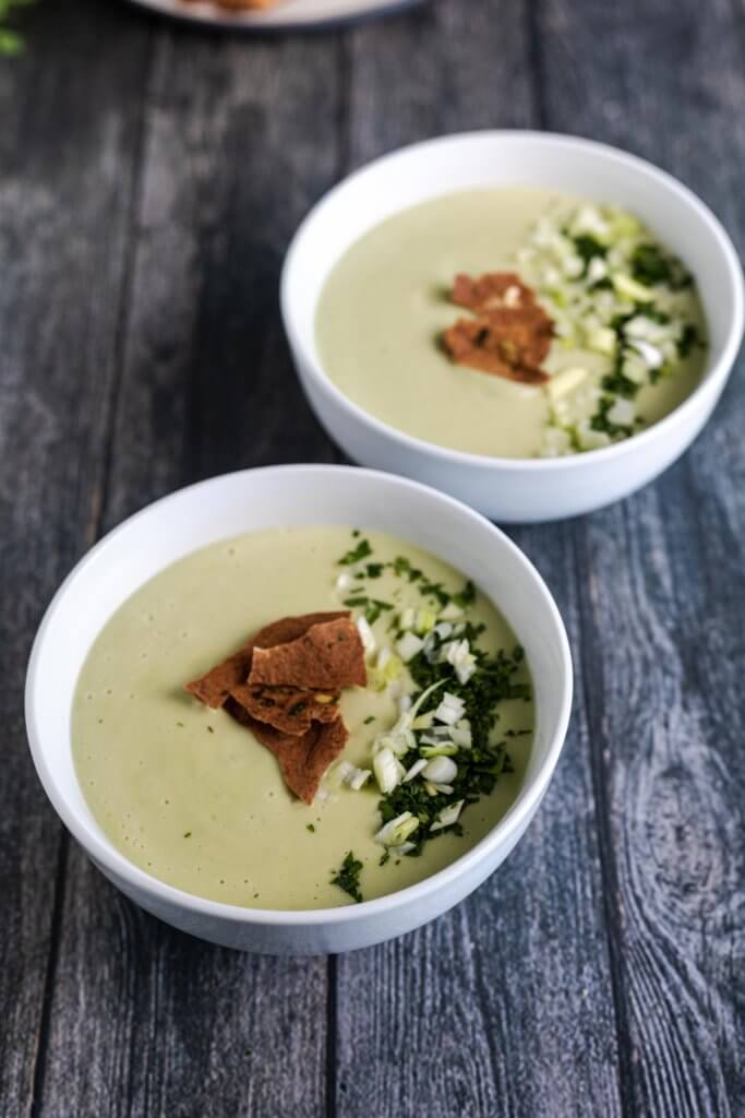 two bowls of vegan cream of celery soup served with toasted pita and herbs