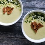 vegan celery soup served in white bowls and garnished with crunchy pita chips