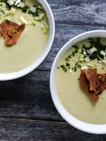 vegan celery soup served in white bowls and garnished with crunchy pita chips