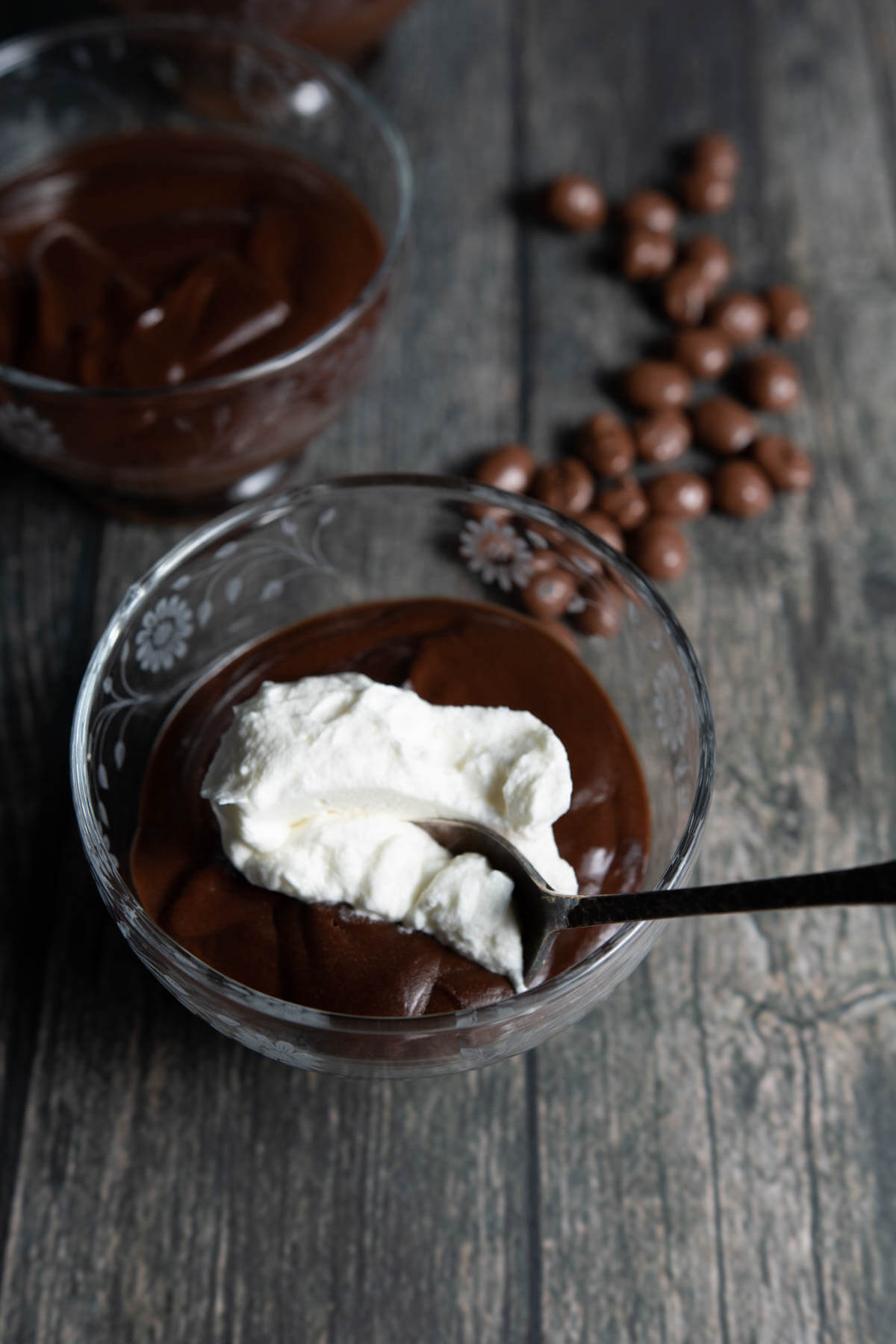 a spoon in a  single serve of pot de creme custard topped with whipped creme and espresso beans