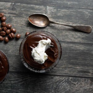 top side view of dark chocolate pot de creme with whipped cream and chocolate covered espresso beans