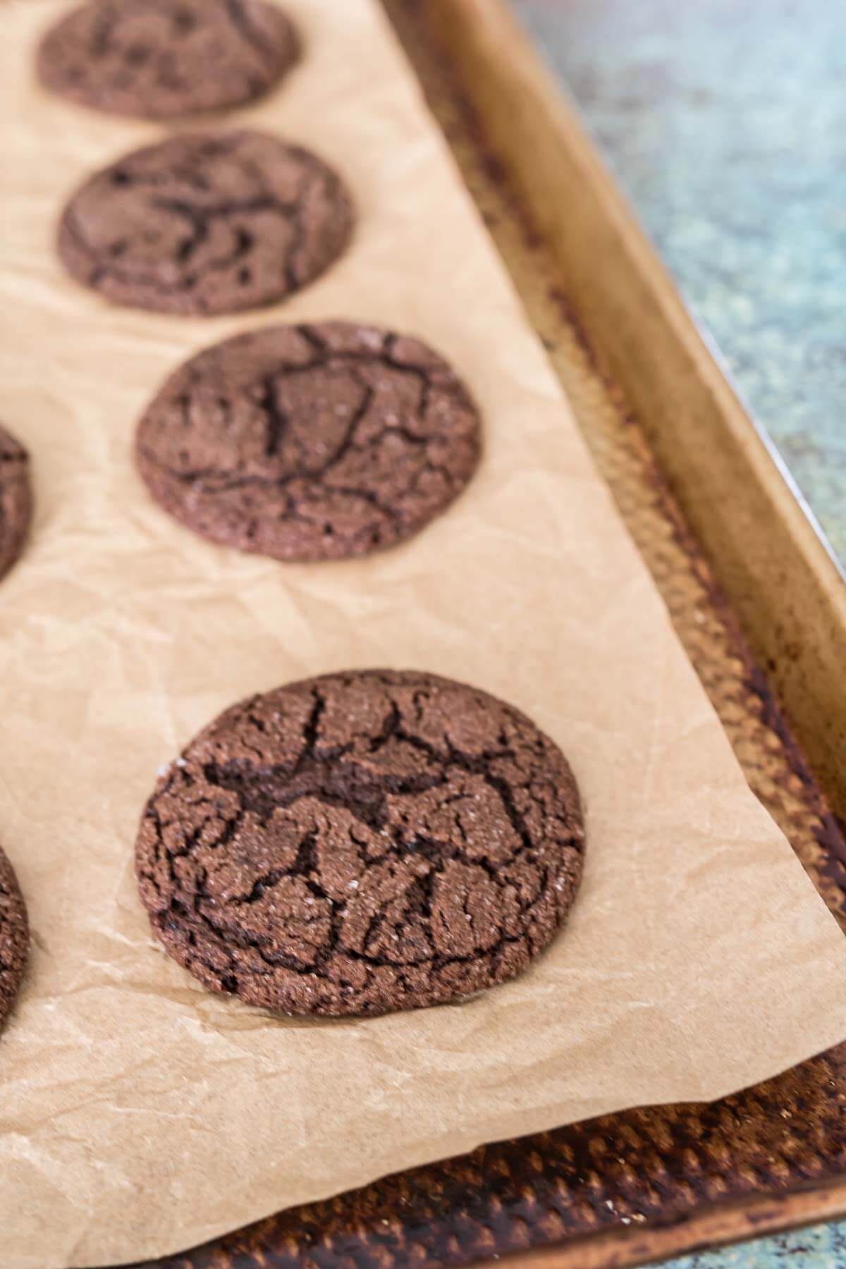 Dark chocolate espresso crinkle cookies on a cookie sheet lined with parchment paper.