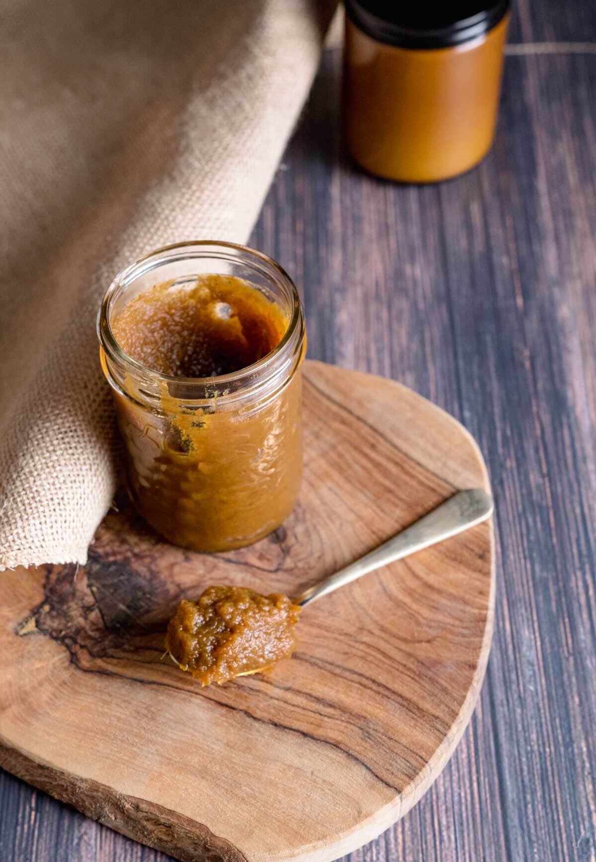 pumpkin butter in a mason jar with a spoon and on a cutting board