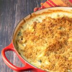 spinach mac and cheese with crispy bread crumb topping in a red casserole dish