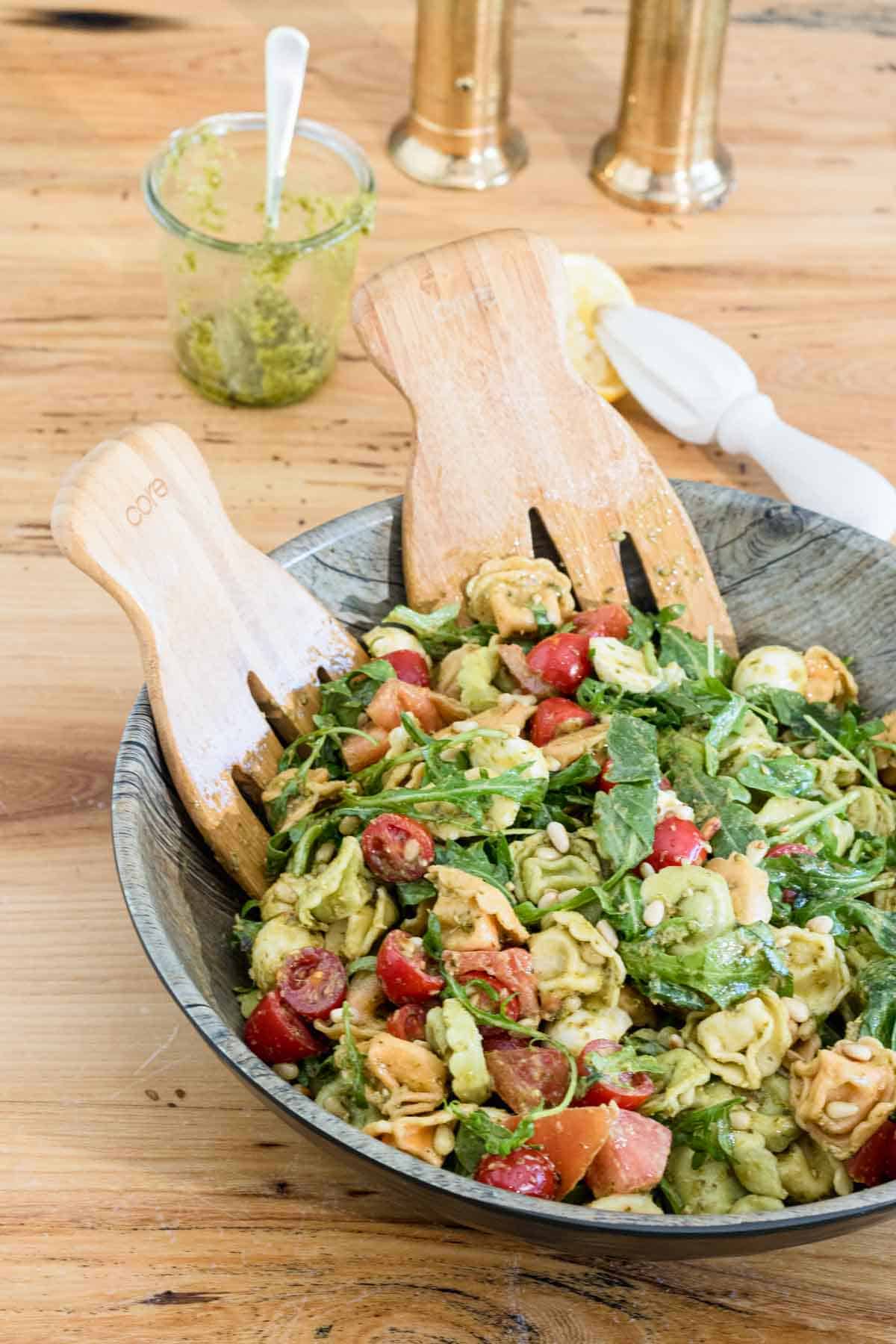 totellini pasta salad with pesto, arugula, cherry tomatoes and bocconcini cheese in a large bowl