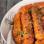 soy glazed sweet potatoes on a serving platter with sesame seeds
