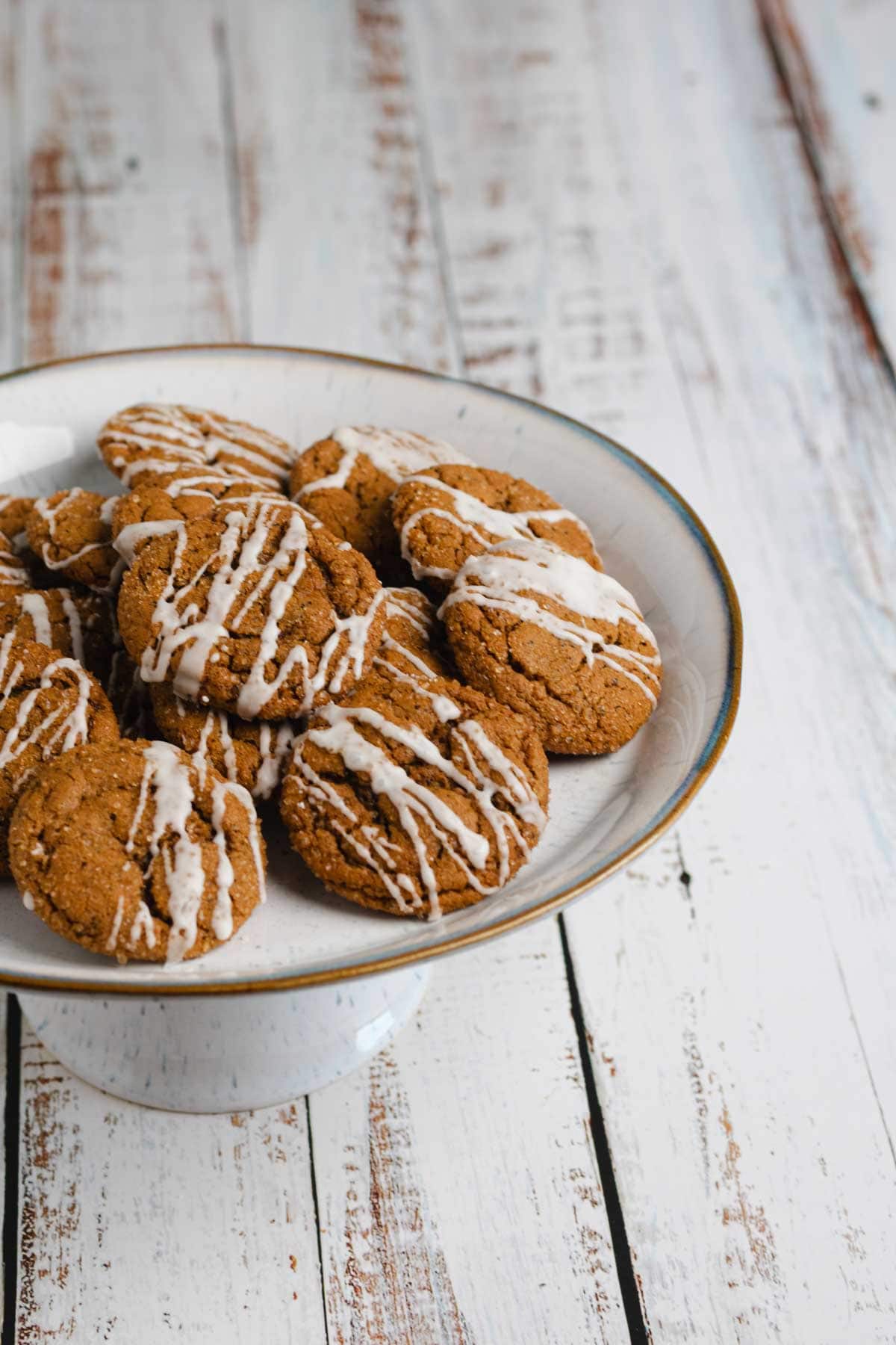Chai ginger molasses cookies with vanilla cream piled on white serving platter.